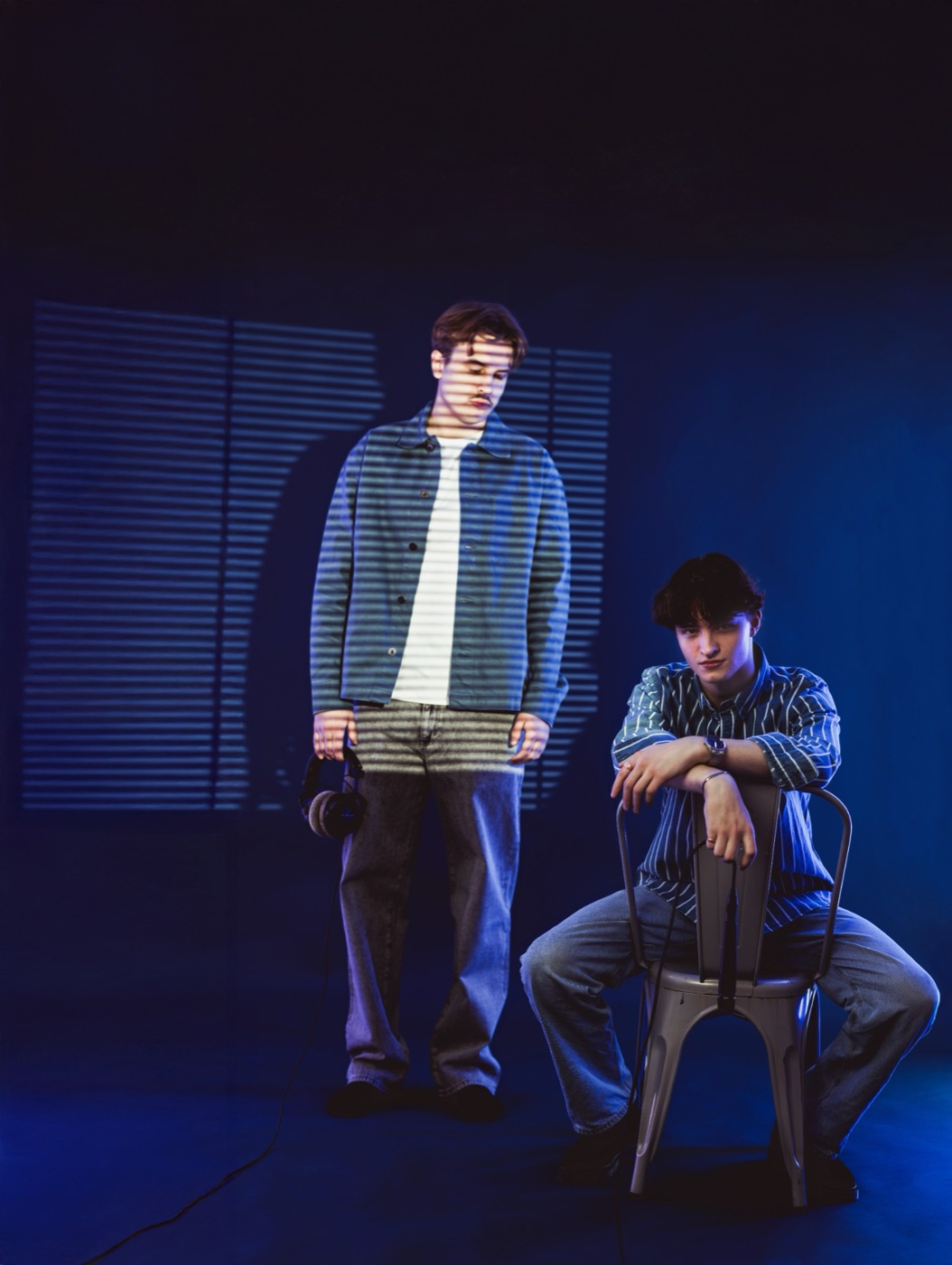 Morris Jones standing and Elvin Sharpe sitting on a chair, lit in blue